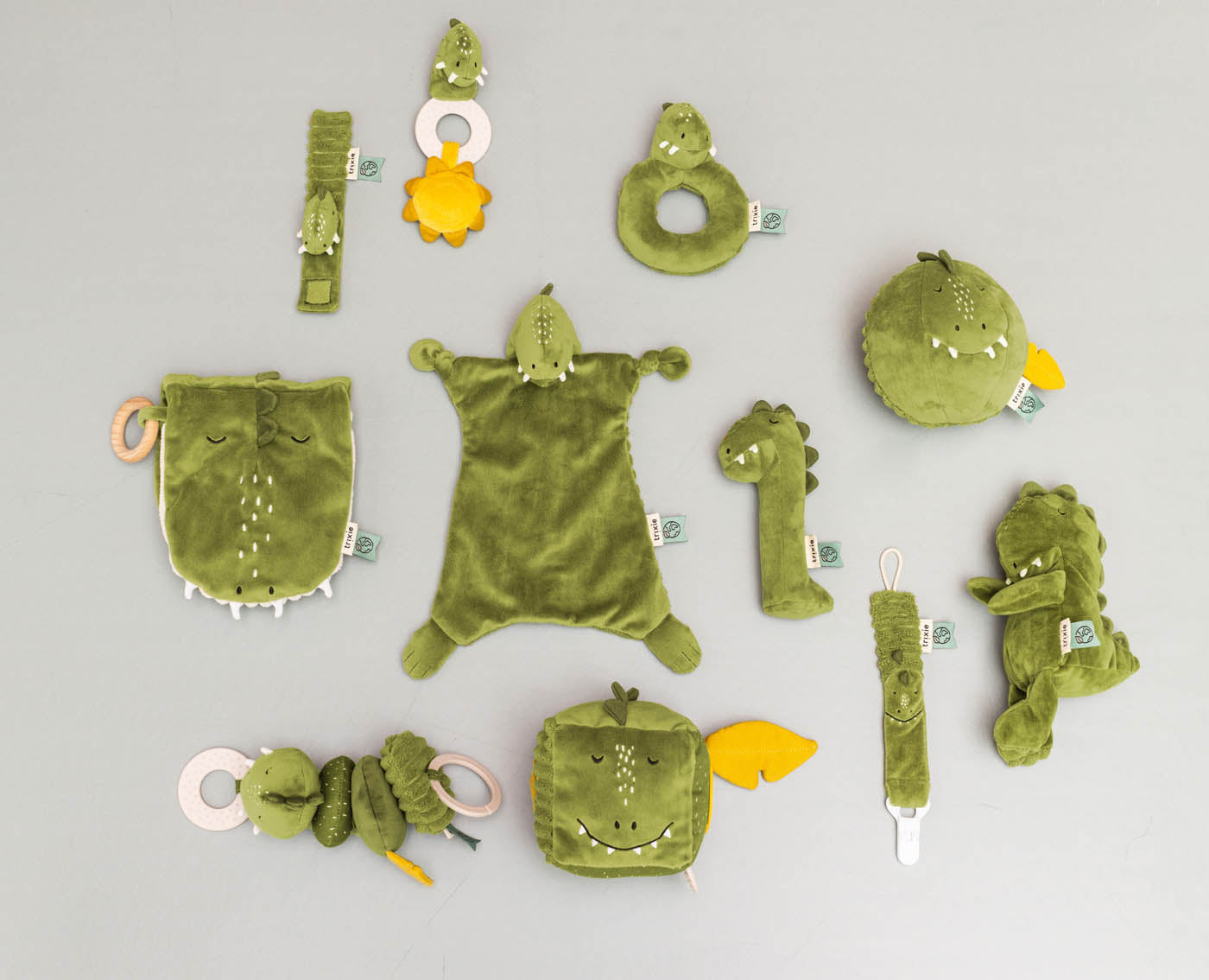 Doudou Mr. Dino Trixie présenté avec les jouets bébé assortis de la collection